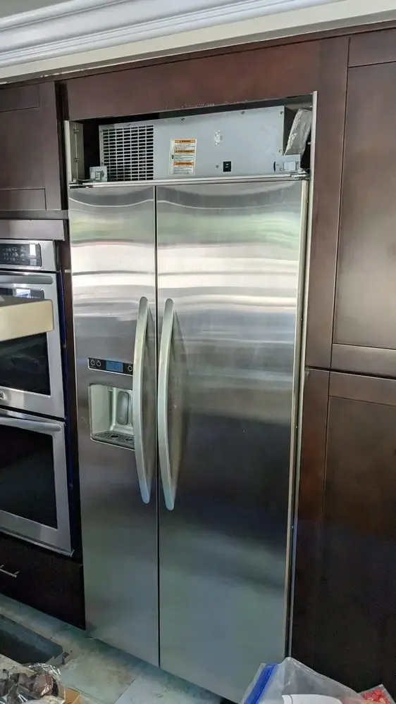 Stainless built-in side-by-side refrigerator with the top grille open for condenser access