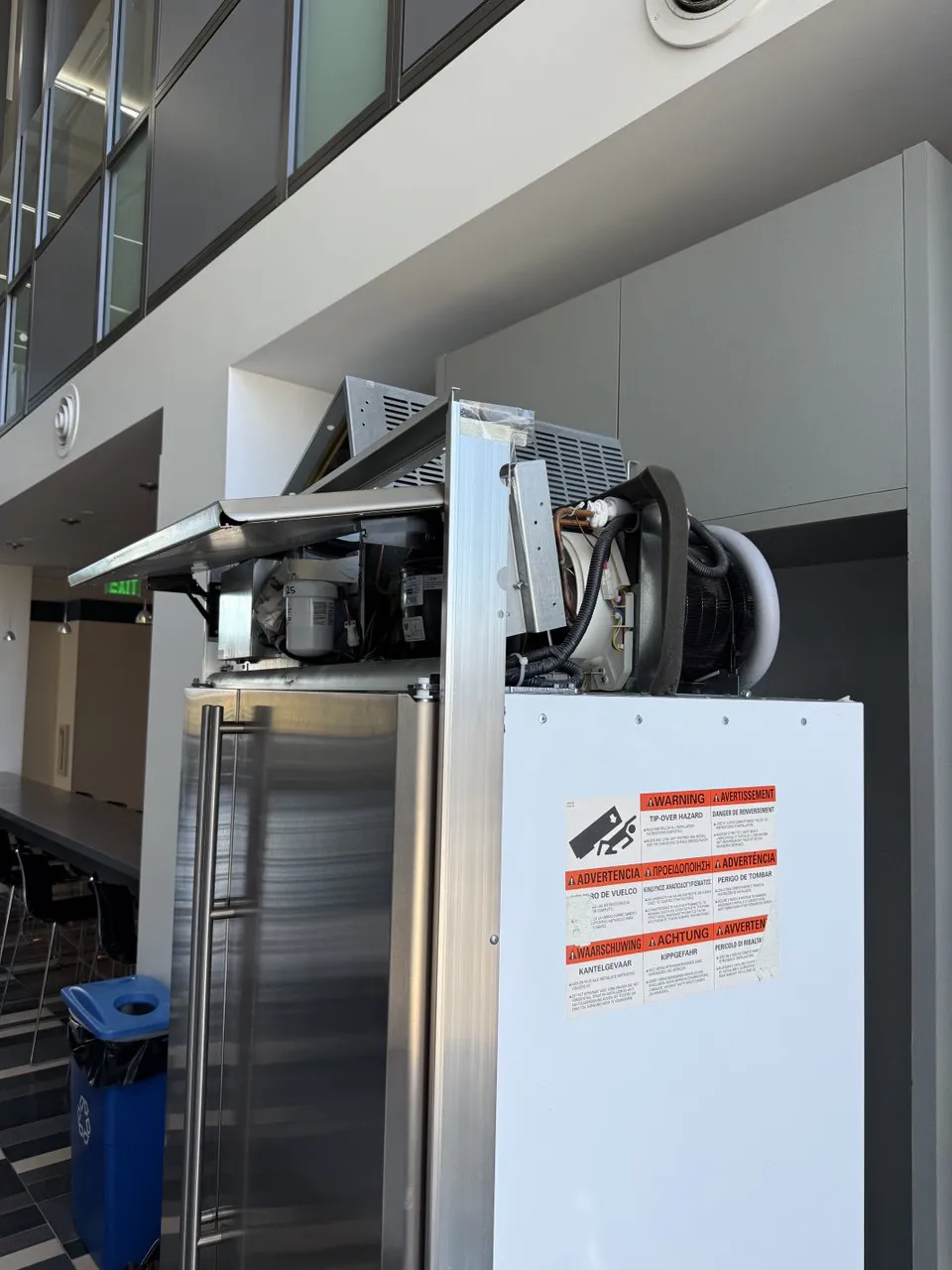 GE Monogram built-in refrigerator with the top machine compartment opened for a refrigerant leak repair