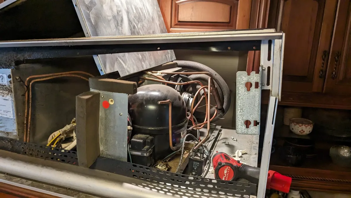 Compressor compartment of a built-in refrigerator opened for sealed-system diagnosis